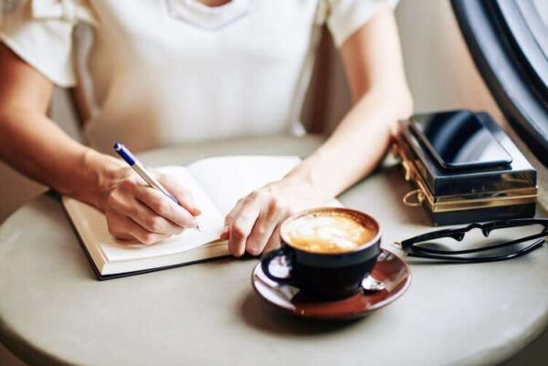 person writing in their intention journals best writing journal