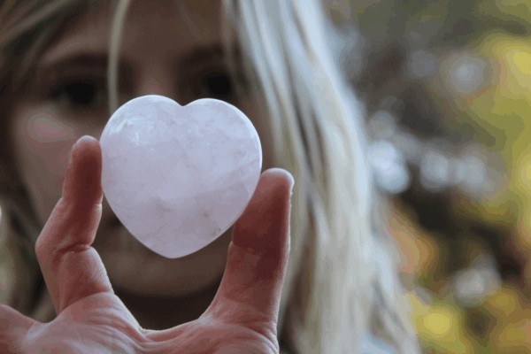 person holding rose quartz crystal heart