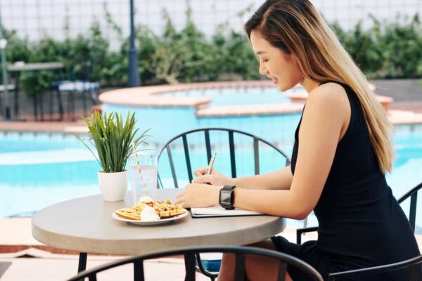 person outside near pool journaling