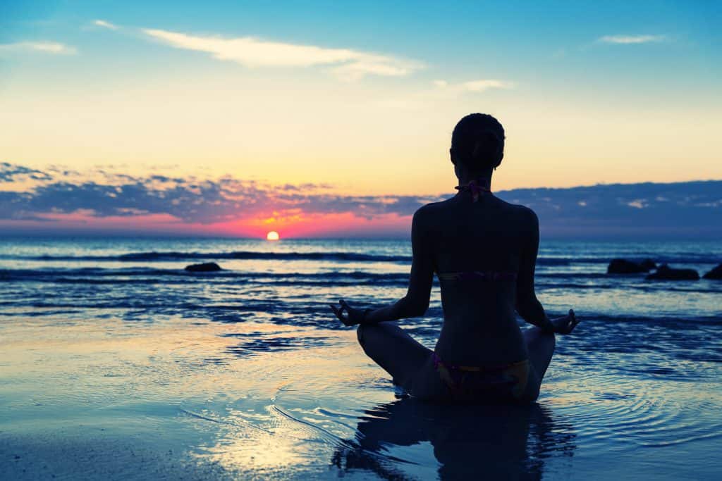 person on beach wondering about the difference between Hypnosis vs Meditation