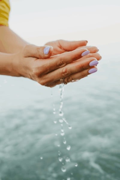 hands holding some salt-water for rose quartz cleanse