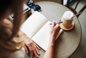 person with coffee and notebook asking themselves can journaling help with mindset and energy