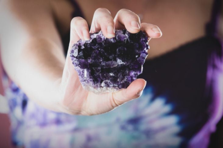 persons hand showing us a piece of amethyst cluster