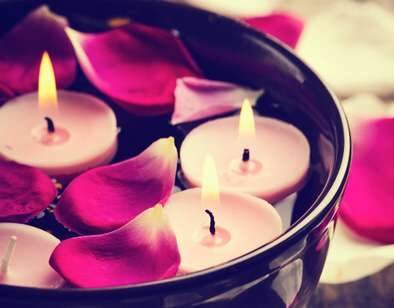 candles floating in water bowl with rose petals