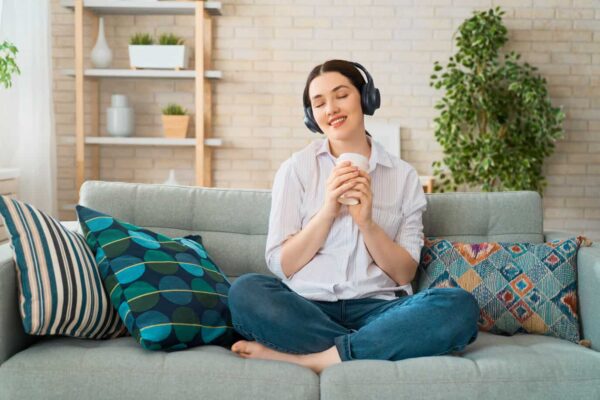 person listening to crown chakra music on headphones sitting on couch