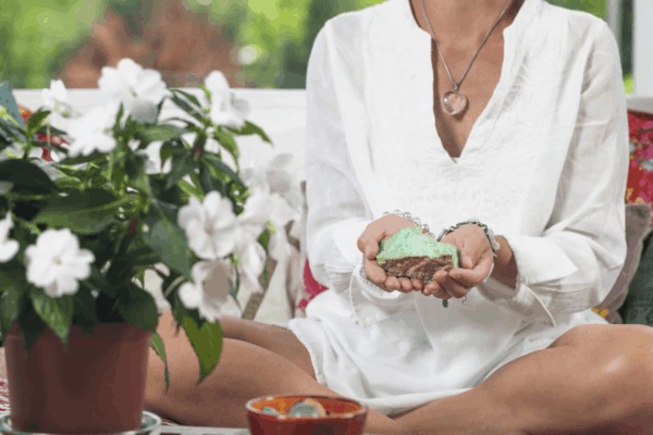 Meditation gifts idea showing a person holding a small green stone next to white flowers