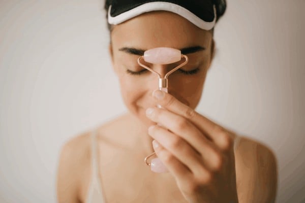 person using rose quartz roller for forehead area