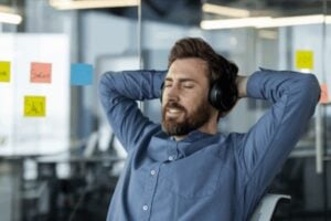 person listening to hypnosis for success on headphones at his desk