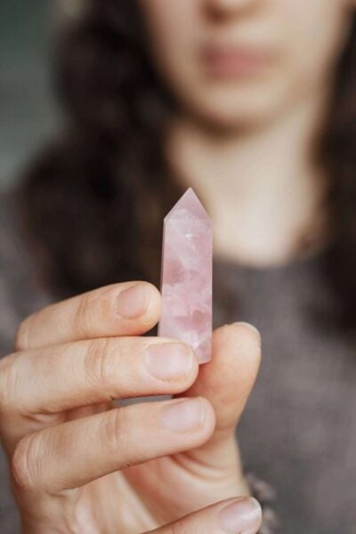 hand holding a rose quartz crystal point