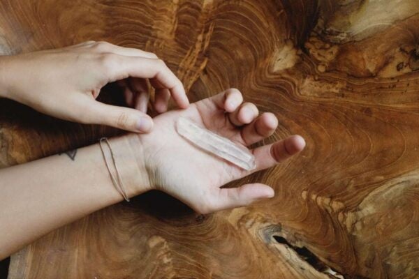 hands with a clear quartz crystal resting in palm