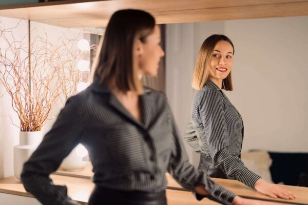 Person looking confidently at their reflection, representing confidence and self-esteem