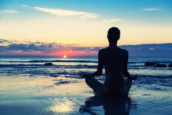 person sitting on the beach wondering about hypnosis vs meditation which one is better