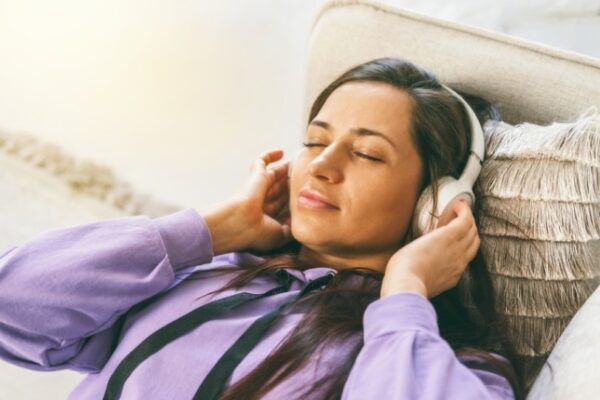 person relaxing on couch using headphones