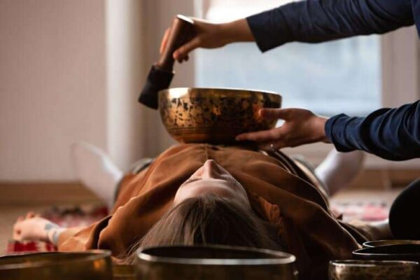 person with a tibetan singing bowl on their chest having sound bath experience