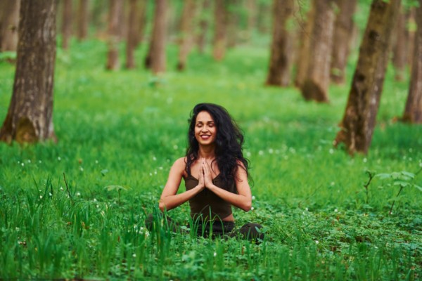 person in prayer outside amongst grass and trees setting intentions spiritually