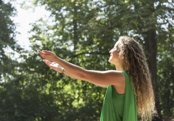 person with arms out into nature setting intentions to manifest