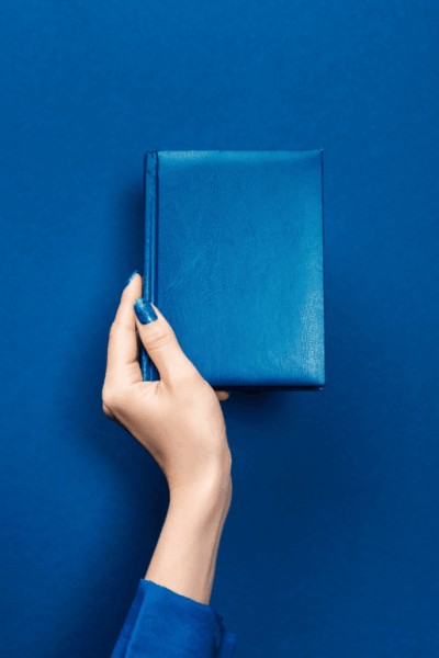 hand holding blue book with powerful throat chakra quotes