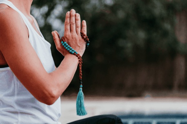 person meditating with blue brown mala beads