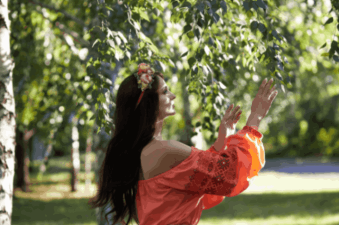 person with their hands in the air feeling the energy of the breeze between the leaves and trees