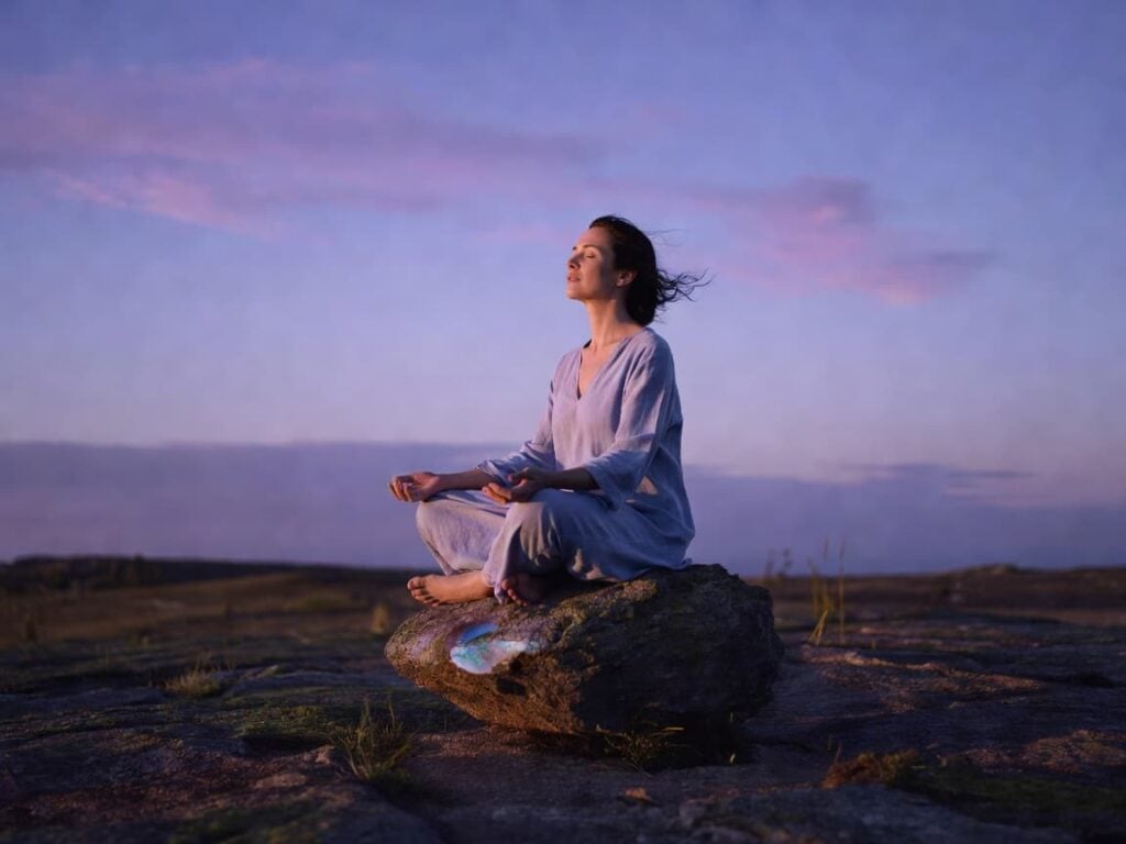 person meditating outdoors wondering what prompts to use in their journal for present moment awareness